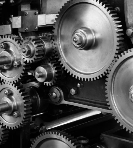 Close-up view of a complex industrial gear mechanism in black and white.